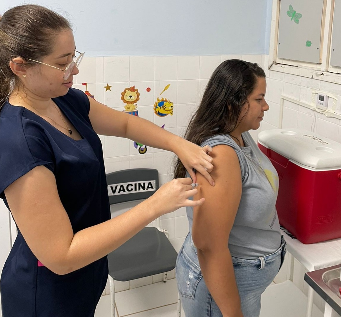 Profissional de saúde aplica vacina no braço de mulher