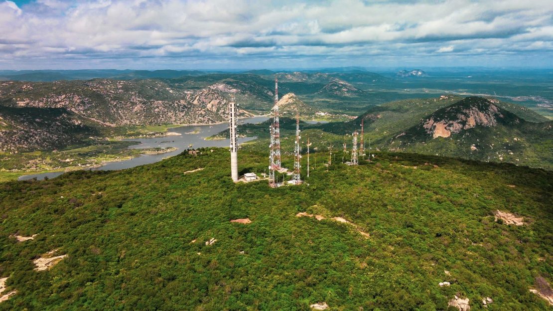 Paisagem de vale verde com lago ao fundo e torres de transmissão